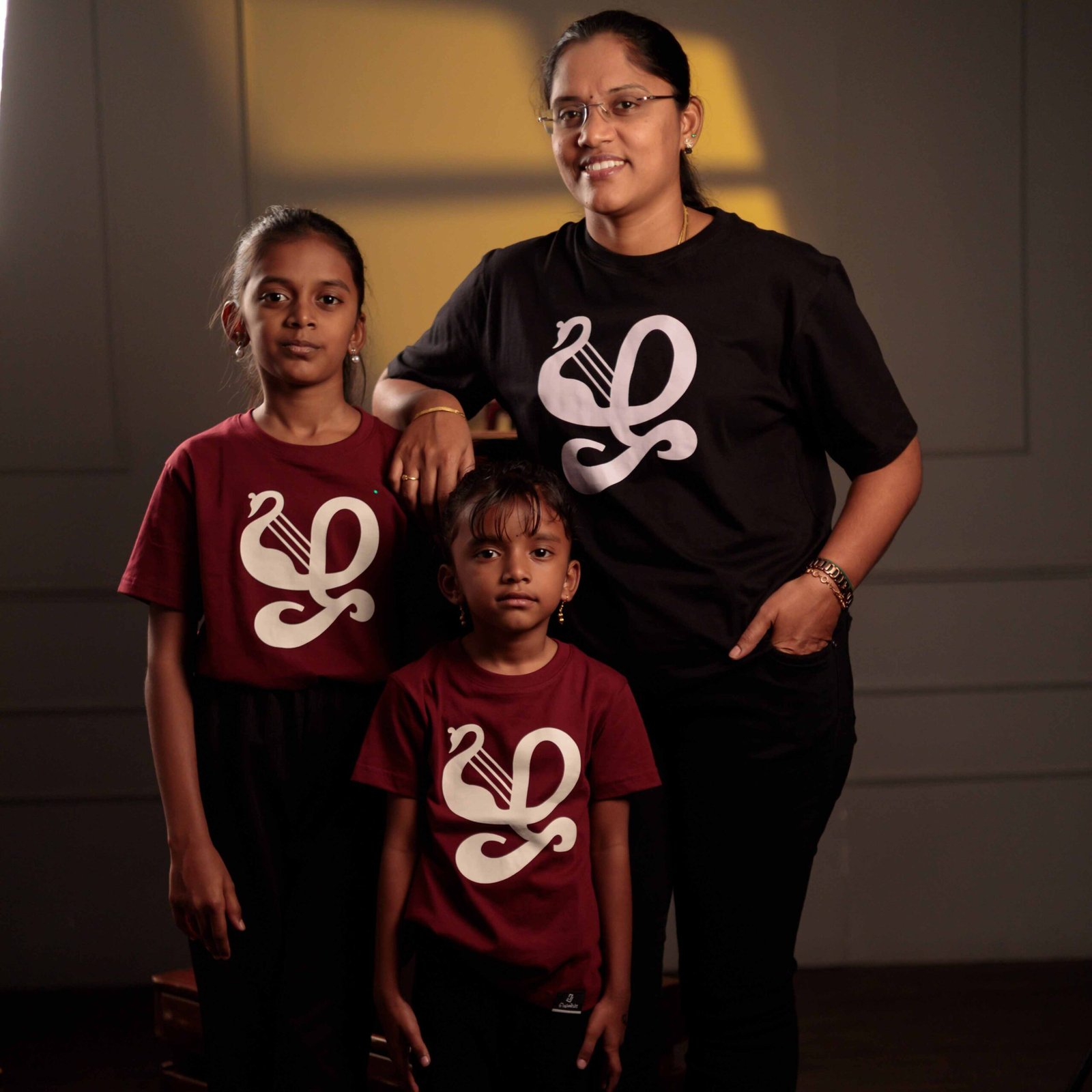 venbaa-family-tamil-Zha-matching-tshirts Adult and children wearing matching Tamil letter ‘ழ’ typography print inspired by ‘யாழ்’, the ancient Tamil musical instrument T-shirts from Venbaa.