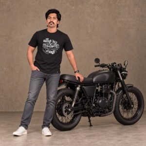 Man wearing a black 'என் மொழி என் வழி' Tamil motorcycle typography t-shirt leaning against a matte black custom motorcycle