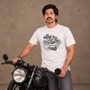 Close-up shot of a man wearing an ecru 'என் மொழி என் வழி' Tamil t-shirt holding the handlebars of a custom matte black motorcycle