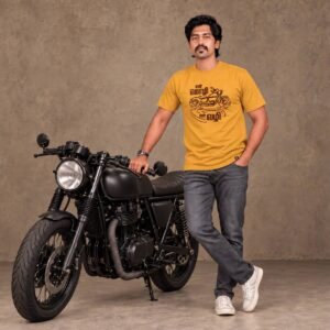 Man standing with one hand in his pocket next to a matte black custom motorcycle wearing a mustard 'என் மொழி என் வழி' Tamil biker t-shirt